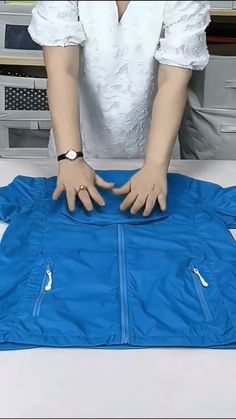 a person is holding their hands over a blue jacket on a table in front of a computer