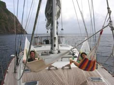 two people sitting in hammocks on the deck of a sailboat