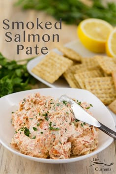 a bowl of smoked salmon pate with crackers and lemons in the background