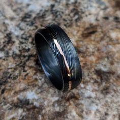 a black ring with gold inlays on a marble surface