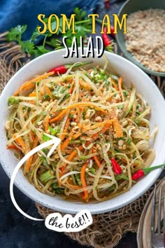 a white bowl filled with noodles and vegetables next to some silverware on a table