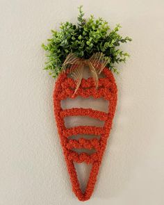 a carrot shaped wall hanging on the side of a wall with plants growing out of it