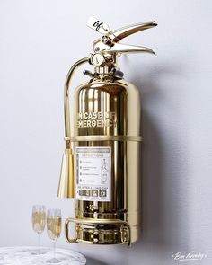 a brass colored fire extinguisher with two glasses on the table next to it