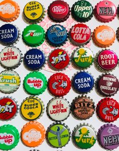 a bunch of bottle caps that are all different colors and sizes on a white surface