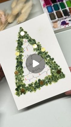 someone holding up a card with a drawing of a cat in the shape of a christmas tree