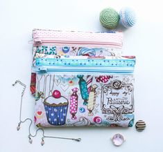 three zippered pouches sitting on top of each other next to beads and pins