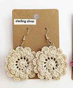 two crocheted flower earrings sitting on top of a card next to a pair of scissors