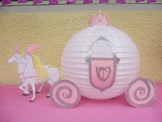 a pink and white paper ball with some decorations on it next to a horse that is wearing a tiara