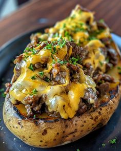 a close up of a baked potato covered in cheese and other toppings on a plate