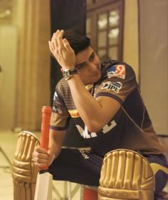 a man sitting on top of a wooden bench holding his hands to his head while wearing a catchers mitt