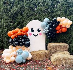 an assortment of balloons and hay bales in front of a fake ghost on the ground