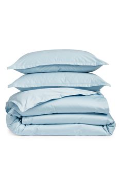 three pillows stacked on top of each other in front of a white background with light blue sheets