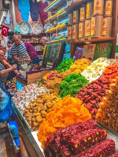 people shopping in an open market with lots of different foods and spices on the shelves