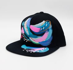 This statement making hat, like a modern painting, stands out with its vibrant colors, brush strokes and one-of-a-kind hand-painted design! This hat is adjustable to fit every head, so you can look and feel like a masterpiece every day! Paint is sealed and protected for weatherproofing. Hat is made of breathable organic cotton, as well as an adjustable back to fit anyone. Hat bill is flat, but can be formed to curve if that is your liking. Modern Adjustable Snapback Hat, Artistic Hand Painted Adjustable Hats, Multicolor Artsy Flat Brim Hat, Black Hand-painted Hat With Curved Brim, Black Hand Painted Hat With Curved Brim, Artsy Multicolor Flat Brim Hat, Hand Painted Black Hat With Curved Brim, Multicolor Adjustable Flat Brim Hat, Adjustable Multicolor Flat Brim Fitted Hat