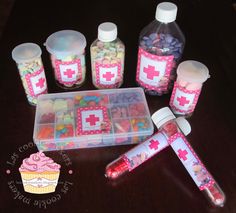 a table topped with lots of bottles and containers filled with candies next to cupcakes