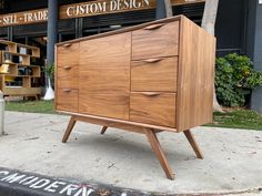 a large wooden cabinet sitting on top of a sidewalk next to a store front window