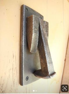 a metal object mounted to the side of a wooden door with two nails on it