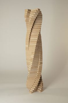 a sculpture made out of wooden planks on a white surface with no one around it