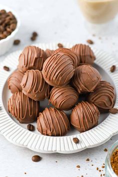 chocolates are on a plate next to bowls of cocoa chips and coffee beans in the background