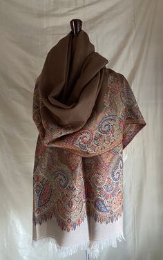 Very Finely woven Cocoa with off white and  multicolor border Kani paisley wool shawl, handwoven in Kashmir, India. This beautiful shawl has a slightly sheer cocoa color interior with a floral jacquard design and a wonderful multicolor paisley border. I show this shawl folded in half lengthwise on the mannequin to show a option to work with the wide width of this shawl. The back of the paisley area has been hand-cut to take away the "floats" to lighten the weight of the border.  This technique is called Kani and is considered a more valuable weaving technique than jamavar weaving.  Jamavar is reversible but not as densely woven as the Kani.  Most of these Paisley shawls are woven as  limited edition groups. This is the last few of a group of 10.  They are collector's items and are a beauti Fantasy Clothing Inspiration, Kashmir Shawl, Paisley Border, Maroon Colour, Paisley Shawl, Kashmir India, Color Interior, Jacquard Design, Fine Craft