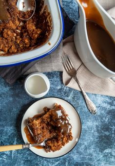 a piece of cake on a plate next to a bowl of syrup and spoons