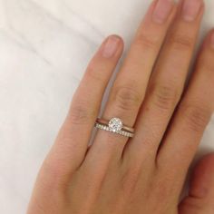 a woman's hand with a diamond ring on her left hand and the other hand holding an engagement ring