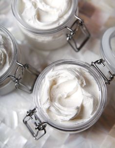 three jars filled with whipped cream sitting on top of a white tableclothed surface