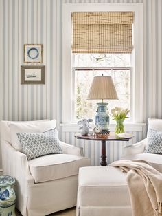 a living room with two white chairs and a small table in front of the window