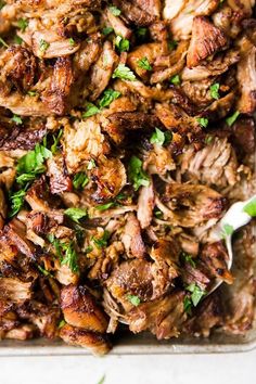 a pan filled with meat and garnished with parsley