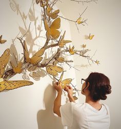 a woman is painting butterflies on the wall