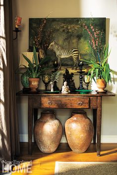 two vases are sitting on a table in front of a painting and zebra figurines