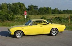 a yellow car is parked on the side of the road in front of a stop sign