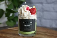 fresh fruit candle with whipped cream and raspberries in it on a wooden table