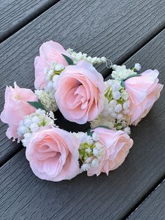 pink roses and white baby's breath are arranged on a bench