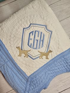 a blue and white quilted blanket with two dogs on it, the monogrammed initials are egh