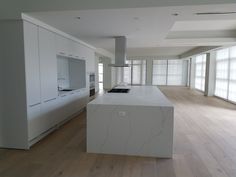 an empty kitchen with white cabinets and marble counter tops in the middle of a large open floor plan