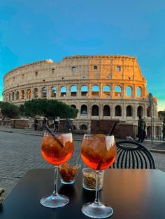 two glasses filled with drinks sitting on top of a table next to an old building