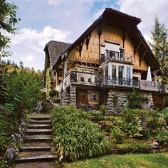 a house that is in the middle of some bushes and trees with stairs leading up to it