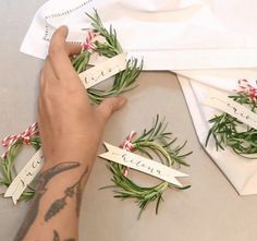 a person is holding some flowers and place cards on the table