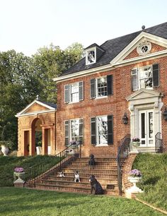 a large brick house with two dogs sitting on the steps