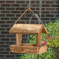 a wooden bird house hanging from a wire