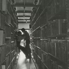 two people standing in the middle of a library filled with books