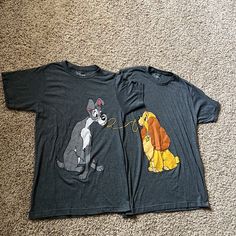 two t - shirts with dogs on them are laying on the floor next to each other