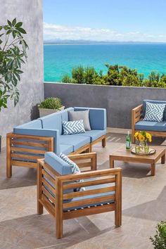 an outdoor patio furniture set with ocean view in the backgrounge and blue pillows