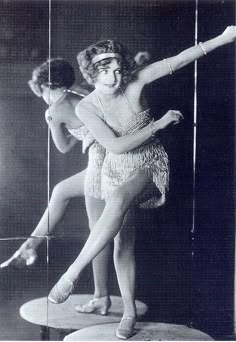 an old black and white photo of two women in flapping garb, one holding a pole