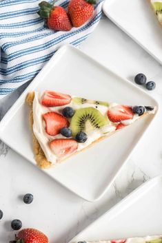 a slice of fruit pizza on a white plate with blueberries and kiwis