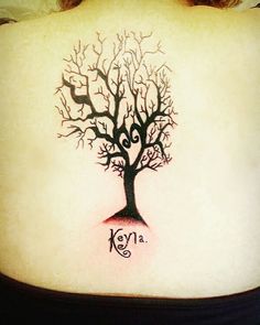 a woman's back with a tree tattoo on her lower back and the word key is written in cursive writing