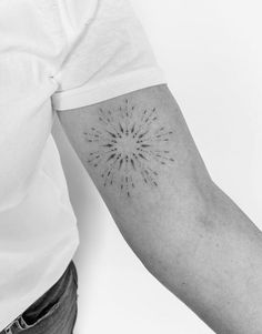 a black and white photo of a person's arm with a starburst tattoo on it