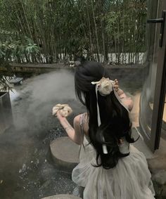 a woman with long black hair standing in front of a steam bath and looking at the water