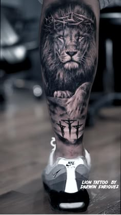 a man's leg with a lion and cross tattoo on the side of his leg